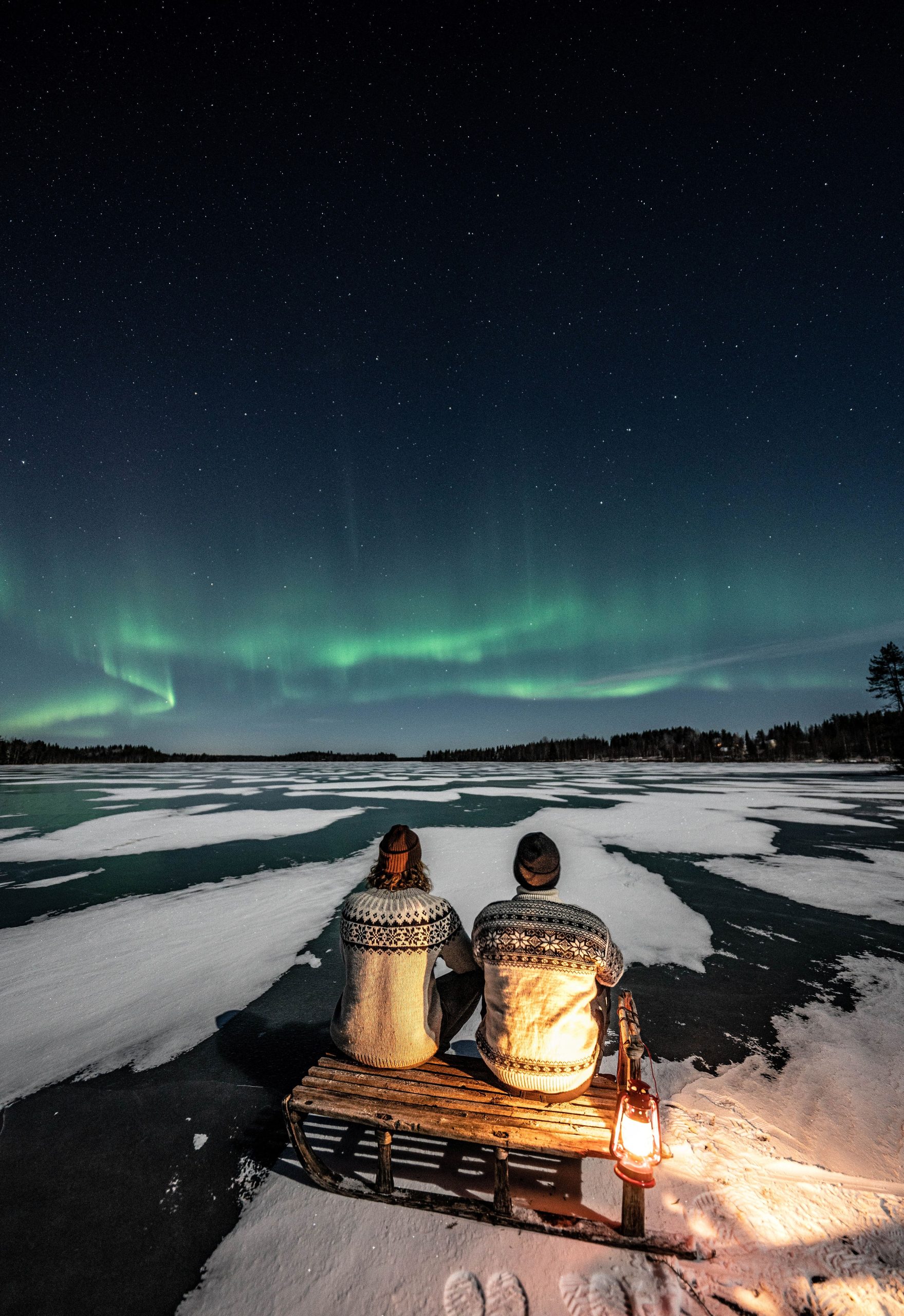 Couple on a sledge under the Northern Lights.